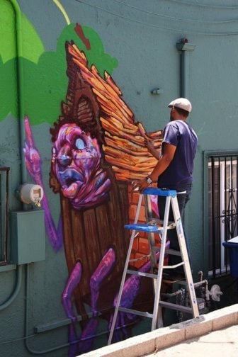 Street artist Ekundayo works on one of his poignant wooden houses for this wall mural